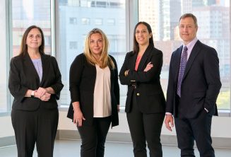 Four Faculty members of different genders stand together, smiling for a photo.