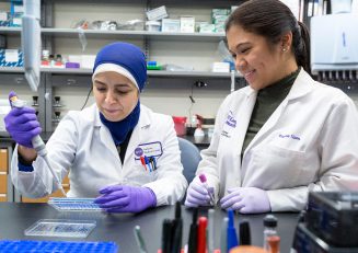 Two female research staff members work together in a laboratory setting.