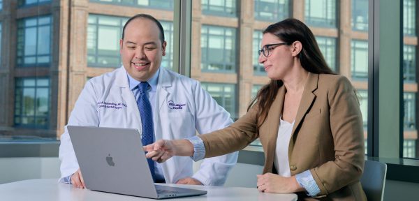 A male physician and a female staff member at NYU Grossman Long Island School of Medicine work together on a laptop.