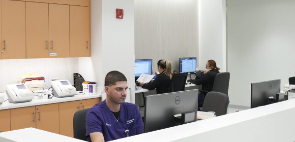 A workstation at an NYU Langone outpatient facility with several staff members working on their computers.