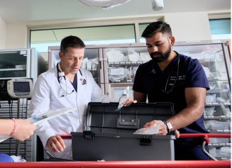 Two male NYU Langone Hospital—Long Island medical staff members check medical stock together.
