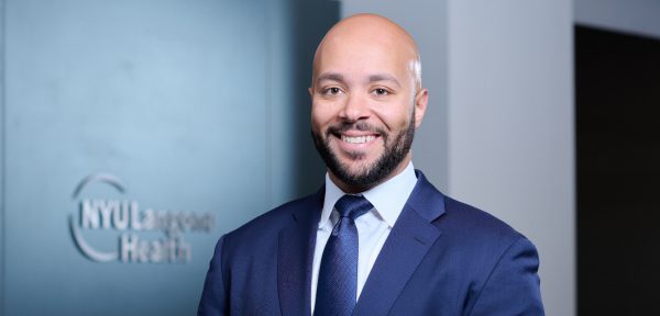 A smiling male staff member at the NYU Langone Health Patient Access Center and Business Office in Nevada.