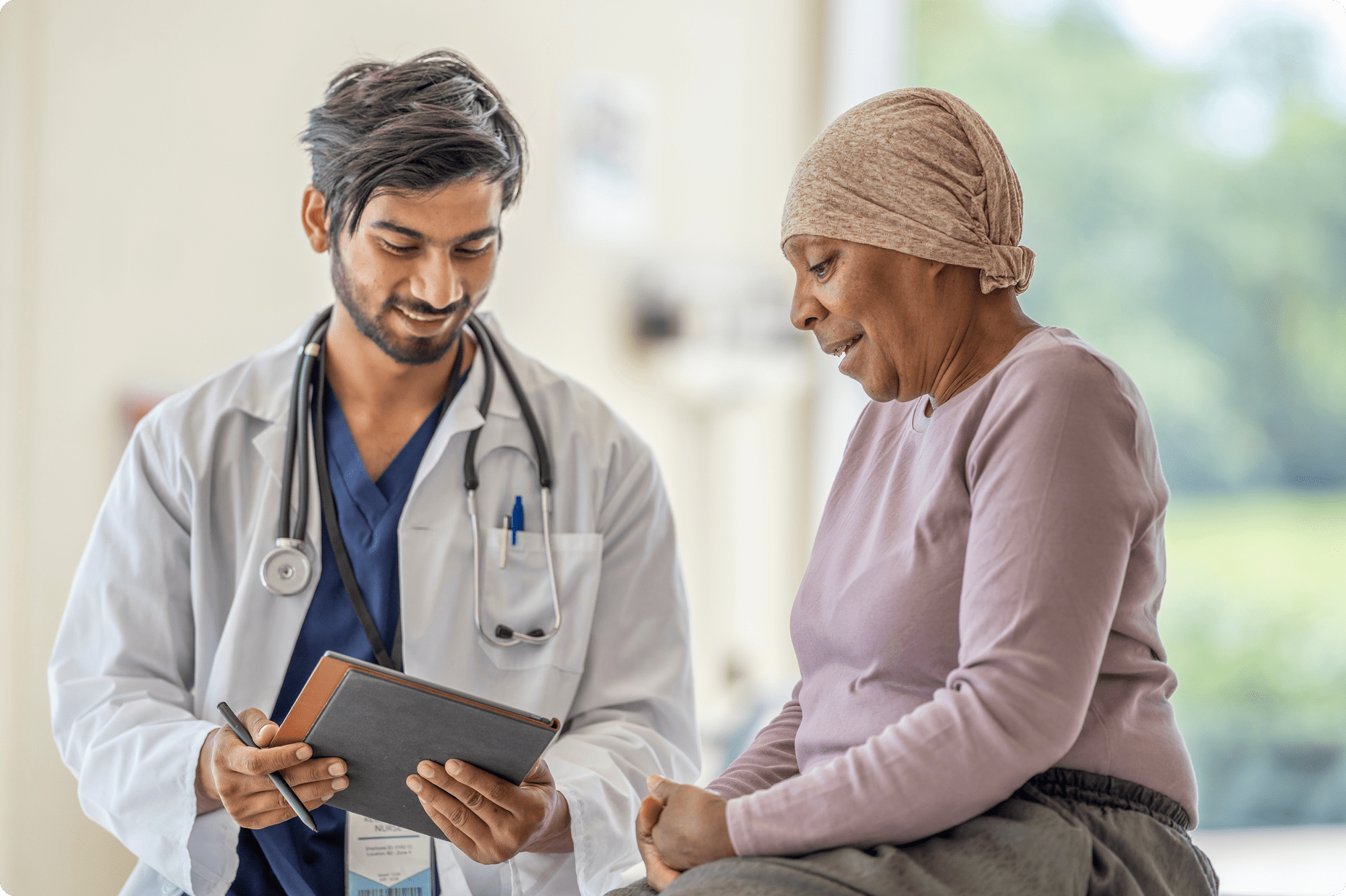 A male NYU Langone doctor talks with a female cancer patient as they look at a chart together.