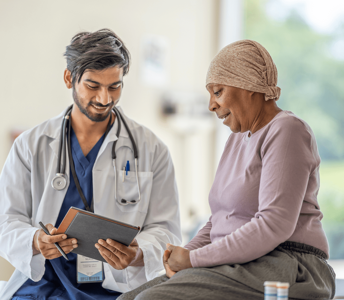 A male NYU Langone doctor talks with a female cancer patient as they look at a chart together.