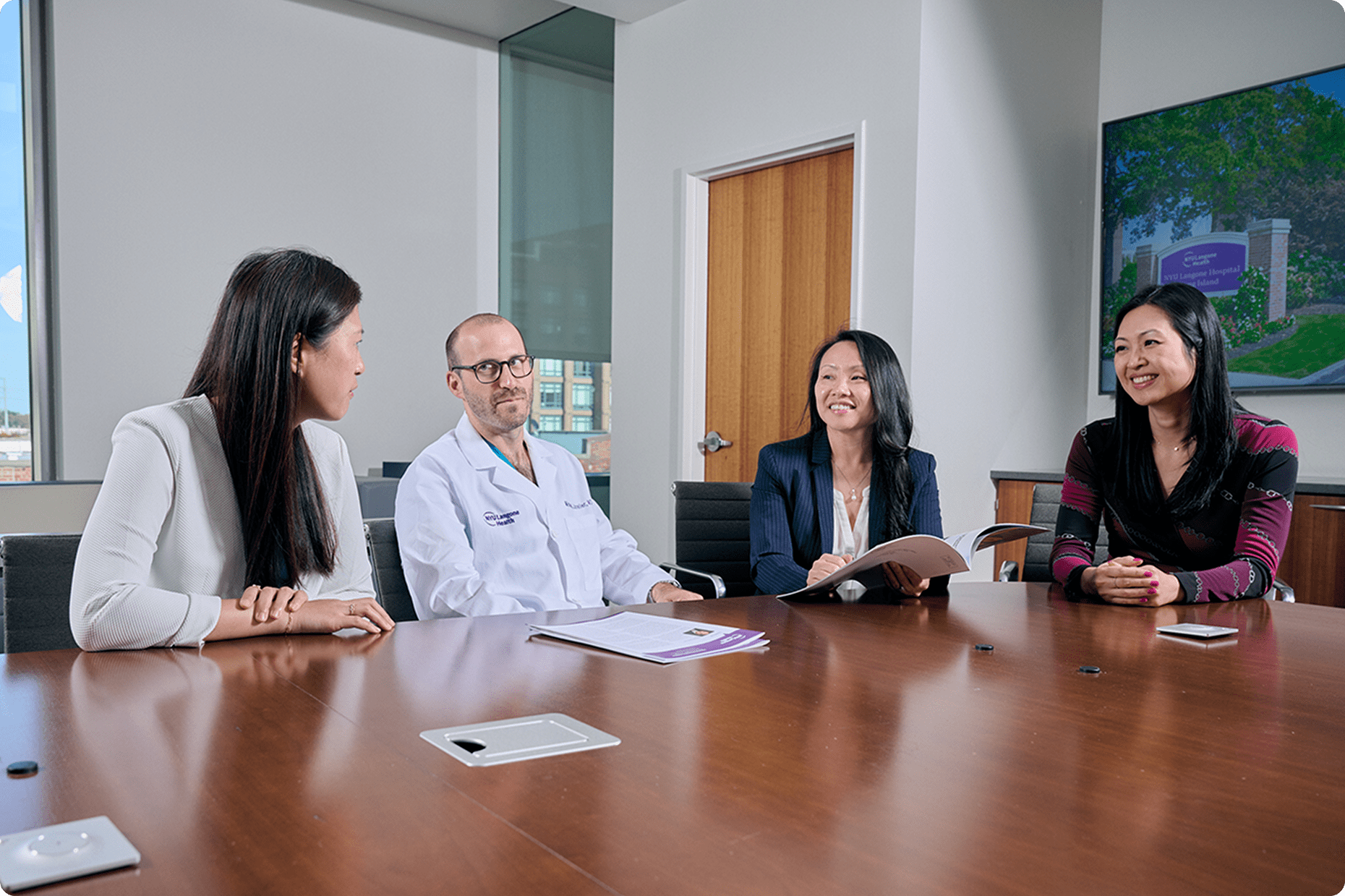 Four staff members from NYU Langone Hospital—Long Island sit at a conference room table, working together.
