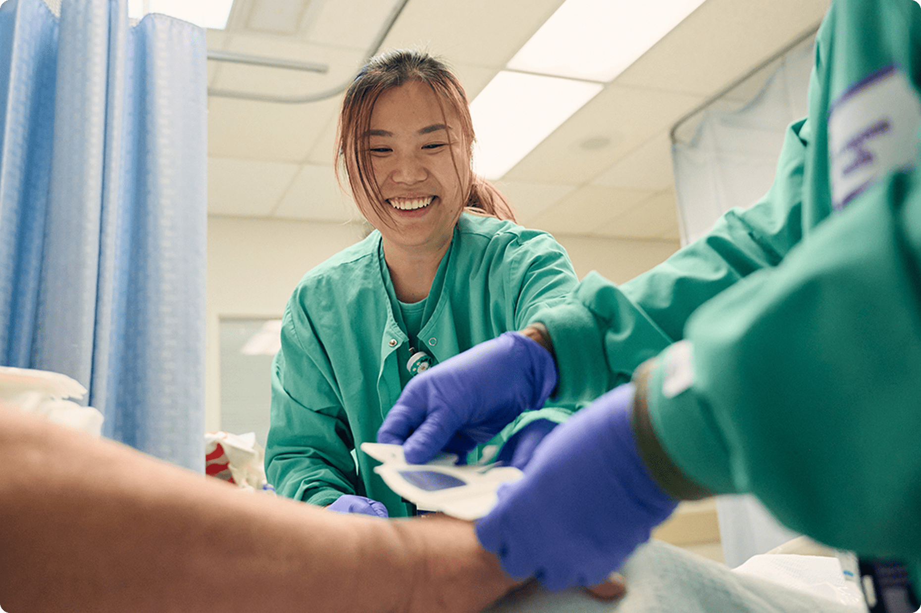 Two medical staff members from NYU Langone Hospital—Long Island provide treatment for a patient at their bedside.