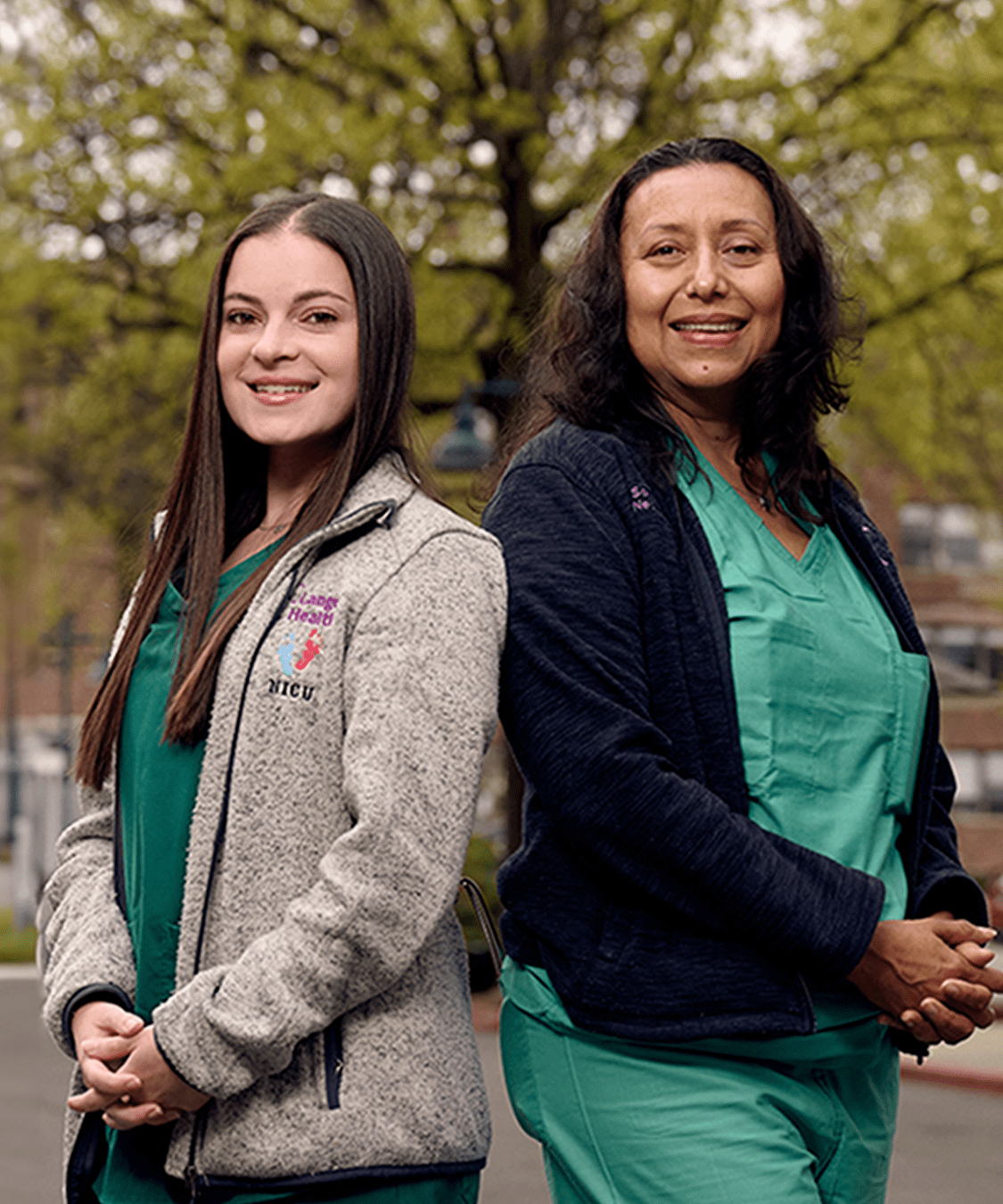 Two staff members from NYU Langone Hospital—Long Island stand side-by-side, smiling in an outdoor setting.