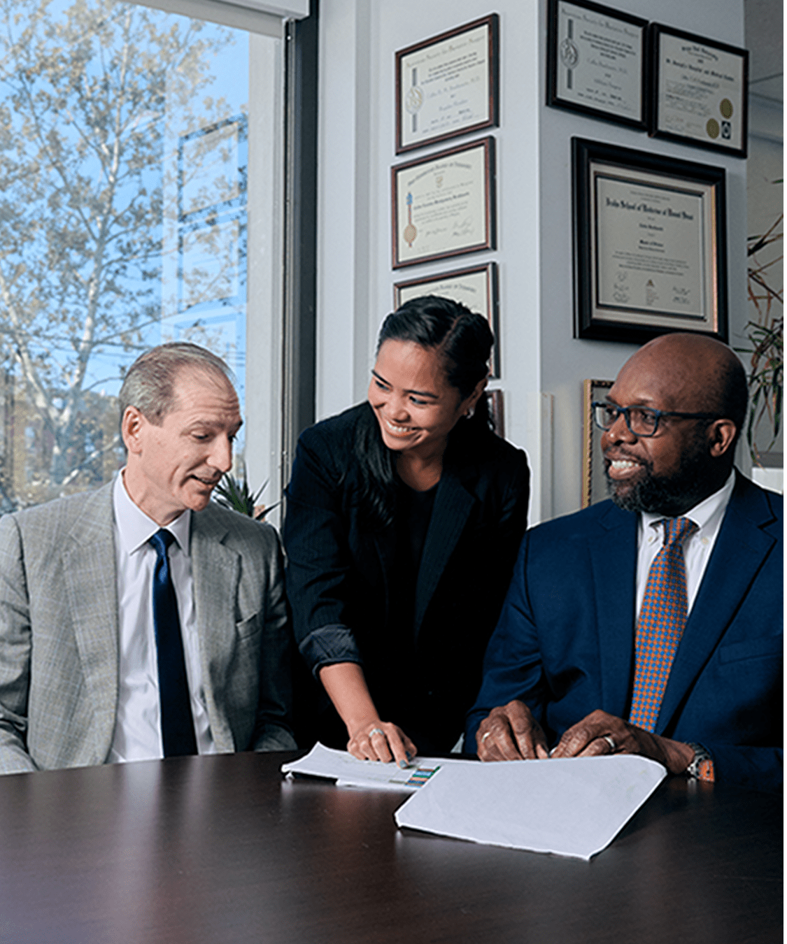 Three NYU Langone staff members discuss details in a document as they work together at a table.