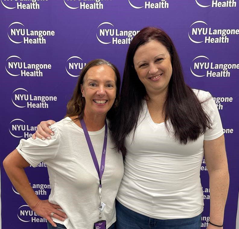 Two female staff members at NYU Langone’s Boynton Beach office stand together and smile as they pose for a picture.
