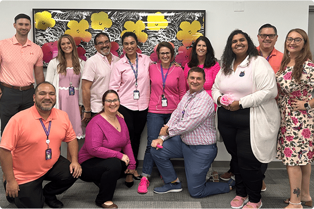 A group of staff members at the NYU Langone's Boynton Beach office smile and pose for a picture.