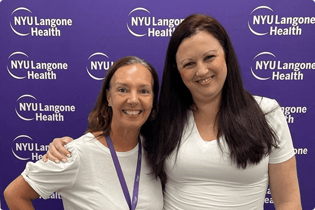 Two female staff members at NYU Langone’s Boynton Beach office stand together and smile as they pose for a picture.