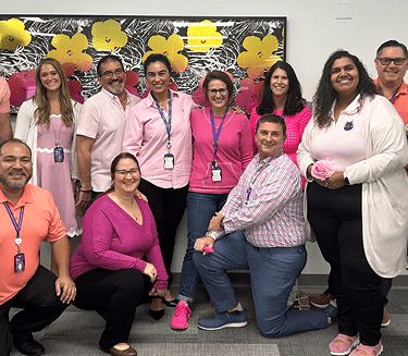 A group of staff members at the NYU Langone's Boynton Beach office smile and pose for a picture.