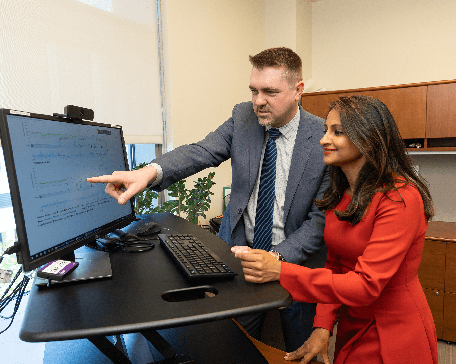 Two office workers at NYU Langone look at a computer screen as they work together at a desk.