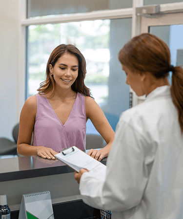 A female staff member talks with a woman at the reception desk of the NYU Langone's Boynton Beach office.