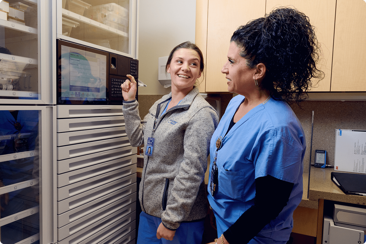 Two nurses at NYU Langone Hospital—Suffolk smiling and interacting in an office.