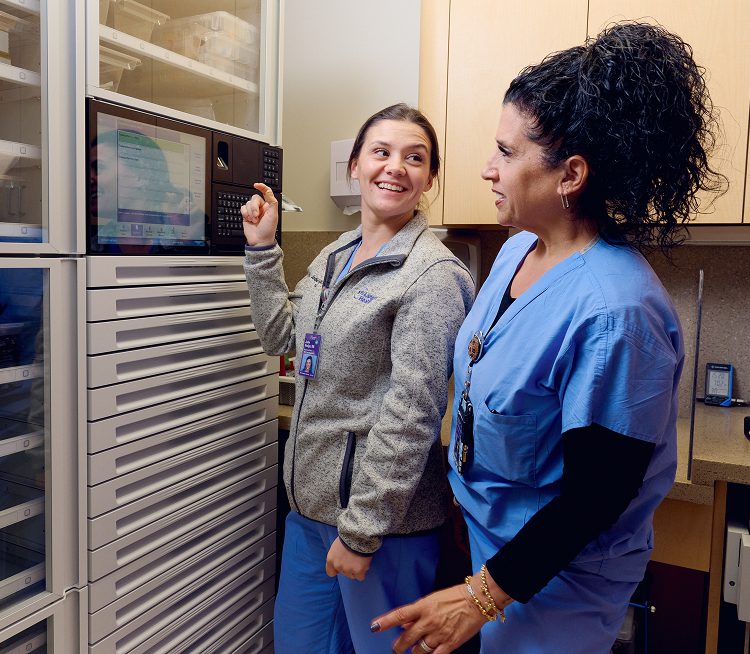 Two nurses at NYU Langone Hospital—Suffolk smiling and interacting in an office.