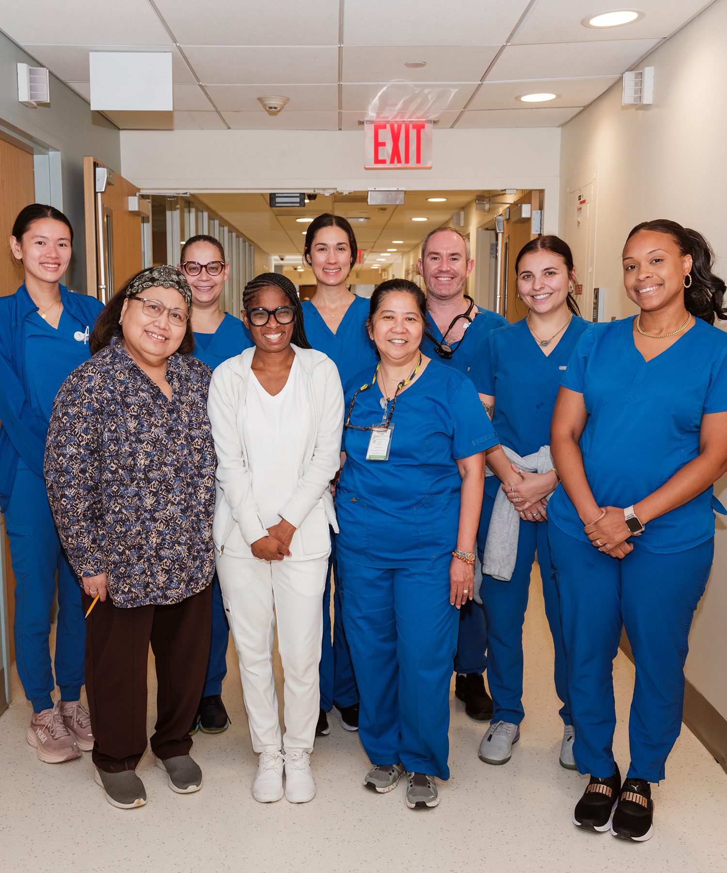 A group of nurses at NYU Langone stand together, smiling in a hospital environment.